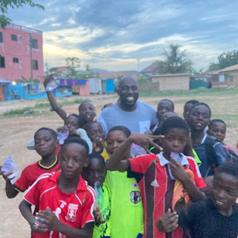 A coach surrounded by cheering children after training