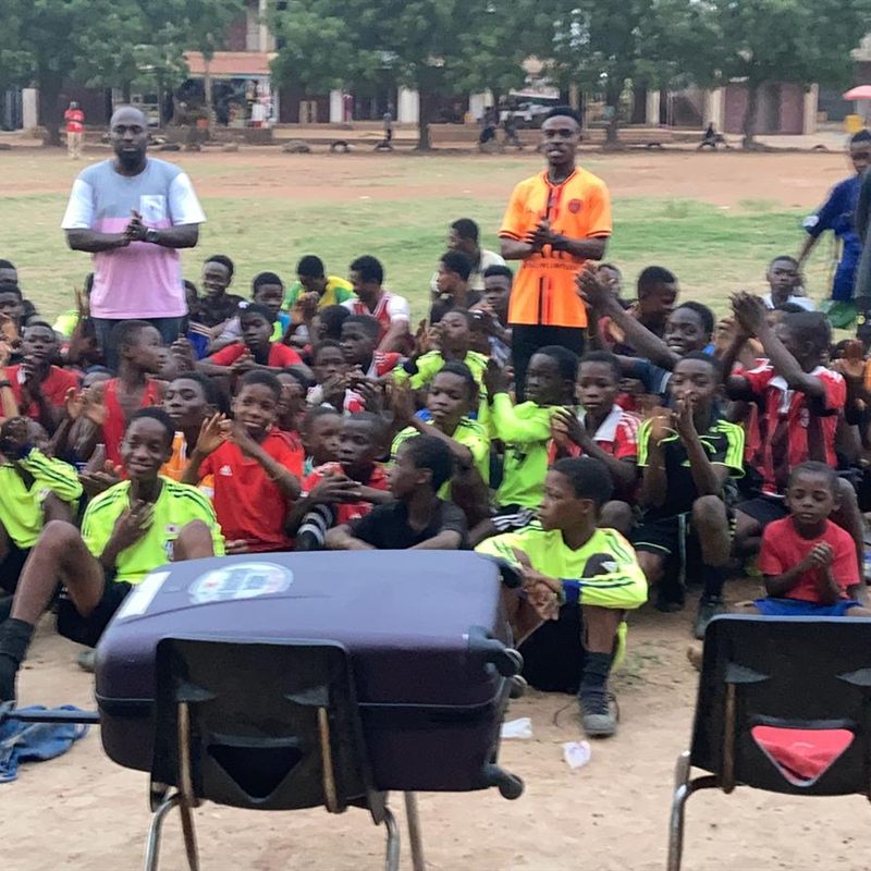 Children seated together on the field with their coaches