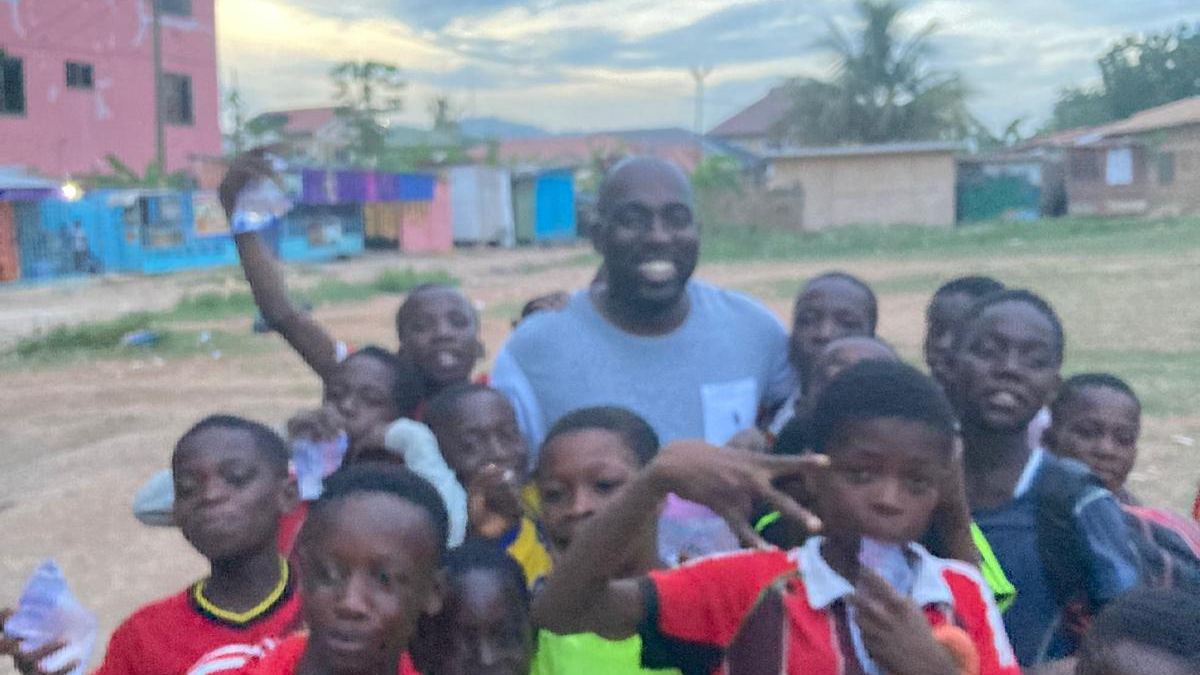 A coach surrounded by cheering children after a training session in Ghana