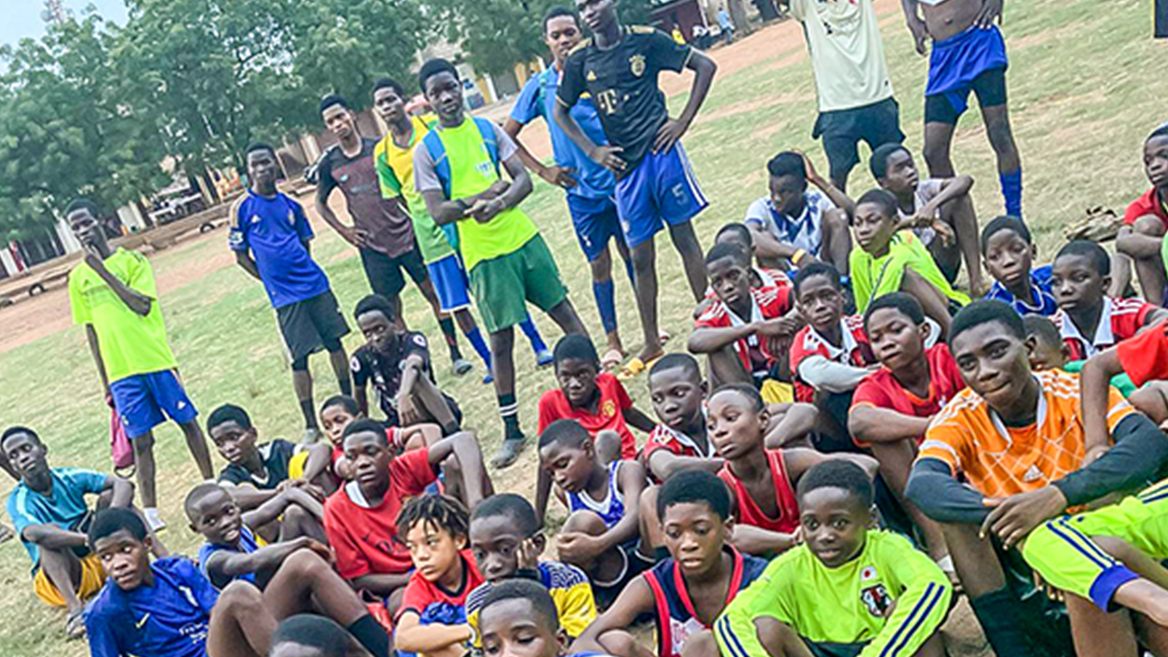 Young footballers gathered together on a pitch in Ghana